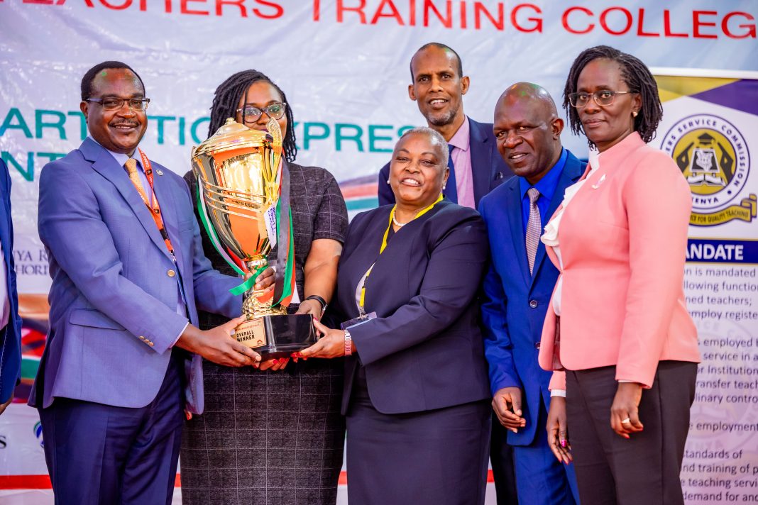Education CS Julius Ogamba (r) and Equity Bank Director Mary Mugwanja (c) award Moi Forces Academy Nairobi at music festival