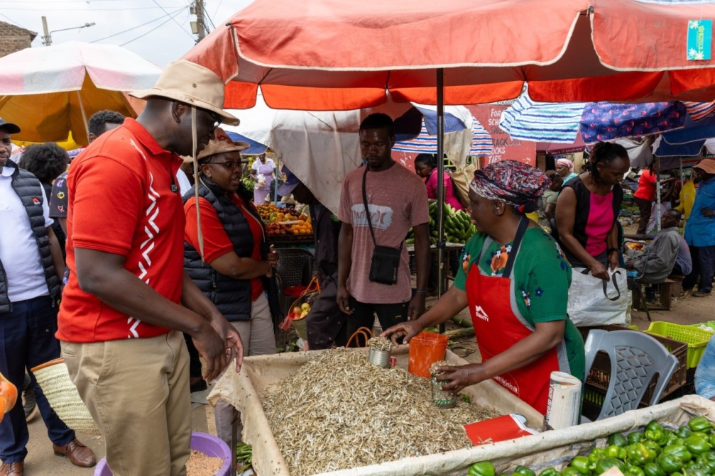 MD Moses Nyabanda engages mama mboga (a groccer) is Kawangware market during launch of Customer Service Week.