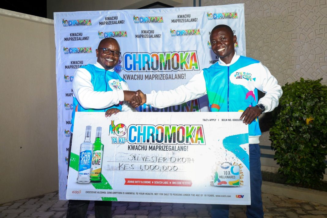 Peter Kathuo, Area Business Development Manager at EABL, presents Sylvester Opiyo as a millionaire winner during the Chromoka campaign activation in Mombasa
