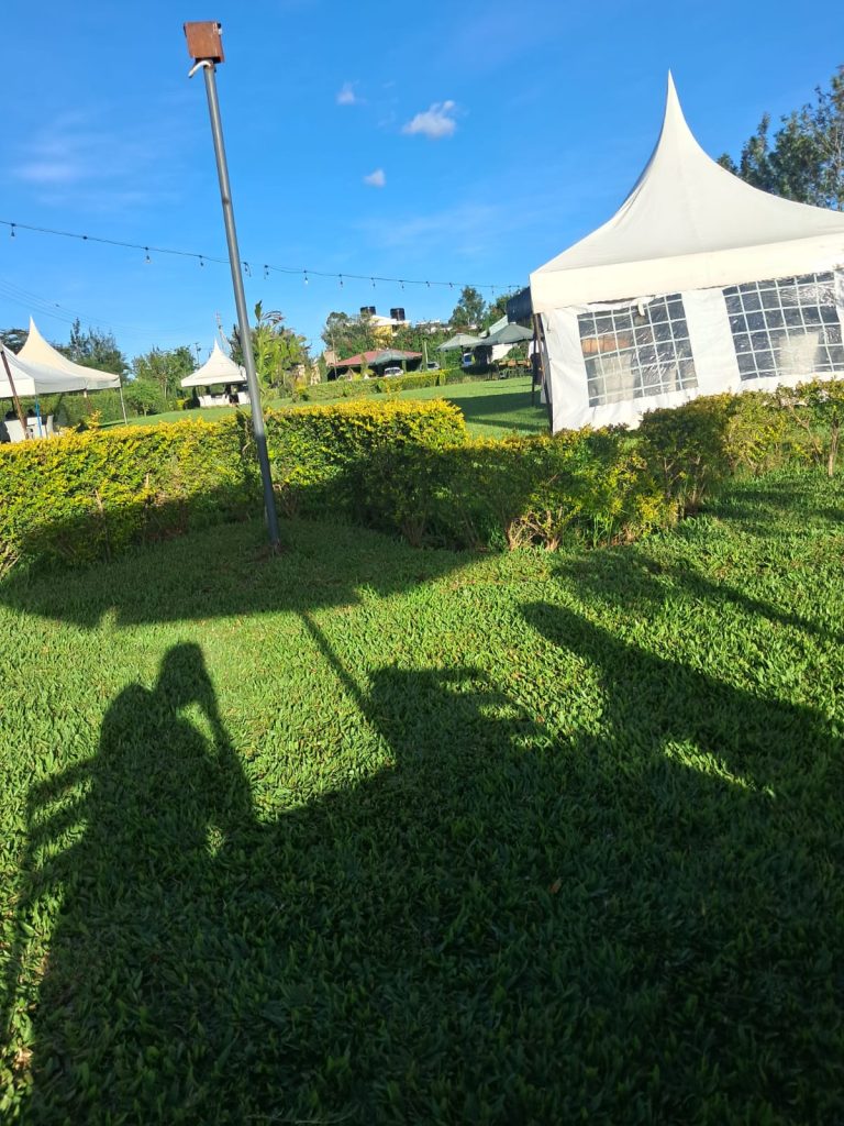 Lush event gardens at Koma Gardens Resort along Kangundo Road, featuring white marquees, manicured hedges, and festive string lighting on a sunny day.